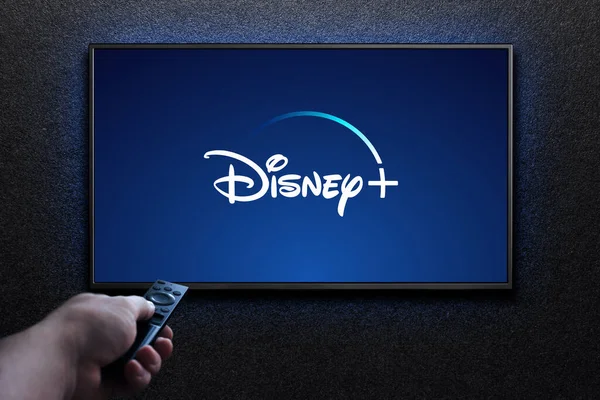 Disney artı logo TV ekranında. Adam uzaktan kumandayla televizyonu açıyor. Disney Plus bir Amerikan abonelik videosu yayınlama servisidir. Astana, Kazakistan - 21 Temmuz 2023.