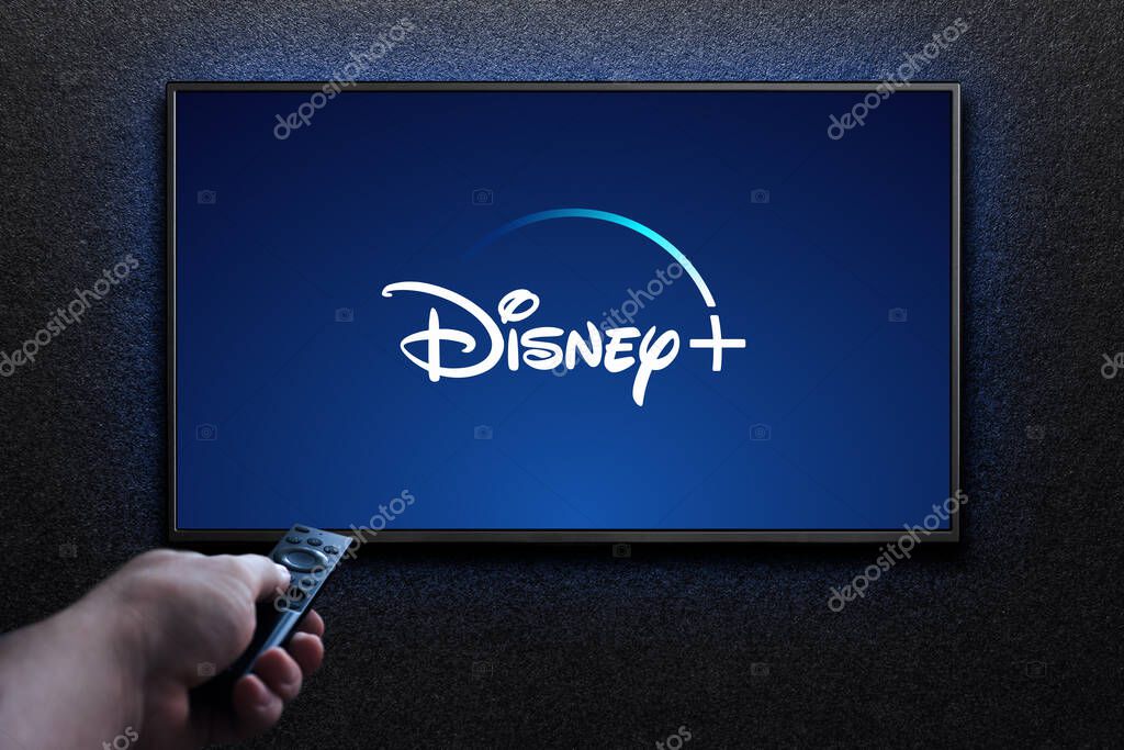 Disney plus logo on TV screen. Man turns on TV with remote control. Disney plus is an American subscription video streaming service. Astana, Kazakhstan - July 21, 2023.