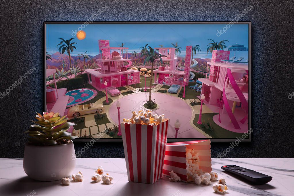 TV screen playing Barbie trailer or movie. TV with remote control, popcorn boxes and home plant. Astana, Kazakhstan - July 2, 2023.