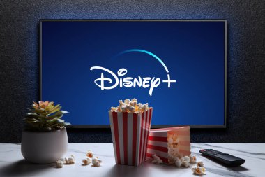 Disney artı logo TV 'de patlamış mısır kutuları, uzaktan kumanda ve masada ev bitkisi. Disney Plus bir Amerikan abonelik videosu yayınlama servisidir. Astana, Kazakistan - 21 Temmuz 2023.