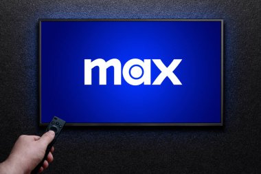 Max veya HBO Max logosu TV ekranında. Adam uzaktan kumandayla televizyonu açıyor. HBO Max, Amerika Birleşik Devletleri 'ne bağlı bir abonelik videosu. Astana, Kazakistan - 21 Temmuz 2023.