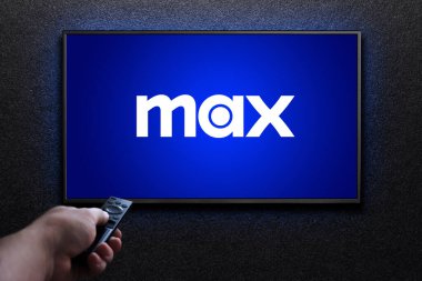 Max veya HBO Max logosu TV ekranında. Adam uzaktan kumandayla televizyonu açıyor. HBO Max, Amerika Birleşik Devletleri 'ne bağlı bir abonelik videosu. Astana, Kazakistan - 21 Temmuz 2023.