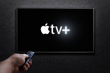 Apple TV artı TV ekranında logo. Adam uzaktan kumandayla televizyonu açıyor. Apple TV + bir Amerikan abonelik yayın hizmetidir. Astana, Kazakistan - 21 Temmuz 2023.