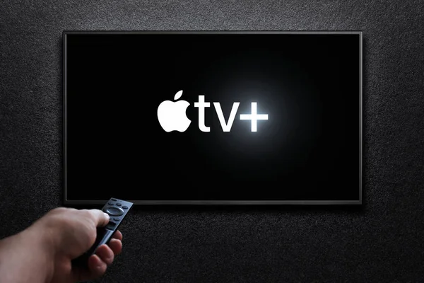 テレビ画面にApple Tvとロゴが付いています 人間はリモートコントロールでテレビに出る Apple はアメリカのサブスクリプションストリーミングサービスです アスタナ カザフスタン 2023 — ストック写真