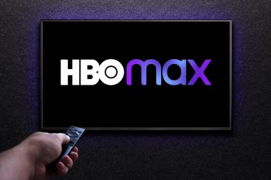 Max veya HBO Max logosu TV ekranında. Adam uzaktan kumandayla televizyonu açıyor. HBO Max, Amerika Birleşik Devletleri 'ne bağlı bir abonelik videosu. Astana, Kazakistan - 21 Temmuz 2023.