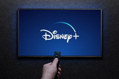 Disney artı logo TV ekranında. Adam uzaktan kumandayla televizyonu açıyor. Disney Plus bir Amerikan abonelik videosu yayınlama servisidir. Astana, Kazakistan - 21 Temmuz 2023.