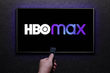 Max veya HBO Max logosu TV ekranında. Adam uzaktan kumandayla televizyonu açıyor. HBO Max, Amerika Birleşik Devletleri 'ne bağlı bir abonelik videosu. Astana, Kazakistan - 21 Temmuz 2023.