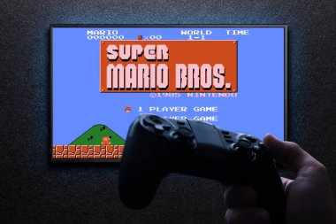 TV 'de Super Mario Bros' un klasik video oyunu. Elinde mavi ışıklı, siyah desenli bir duvar var. Bilgisayar konsepti için Retro oyun öykünücüsü. Astana, Kazakistan - 31 Ağustos 2023.