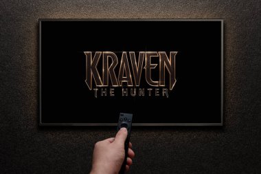 Avcı Kraven ya da TV ekranındaki film. Adam uzaktan kumandayla televizyonu açıyor. Astana, Kazakistan - 8 Eylül 2023.