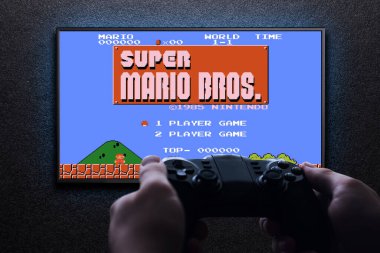 TV 'de Super Mario Bros' un klasik video oyunu. Elinde mavi ışıklı, siyah desenli bir duvar var. Bilgisayar konsepti için Retro oyun öykünücüsü. Astana, Kazakistan - 31 Ağustos 2023.