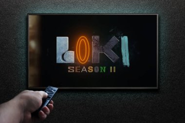 Amerikan televizyon dizisi Loki fragmanı ya da TV ekranındaki film. Adam uzaktan kumandayla televizyonu açıyor. Astana, Kazakistan - 5 Ekim 2023.