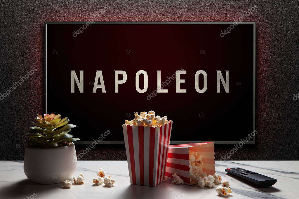 Napoleon trailer or movie on TV screen. TV with remote control, popcorn boxes and home plant. Astana, Kazakhstan - July 21, 2023.