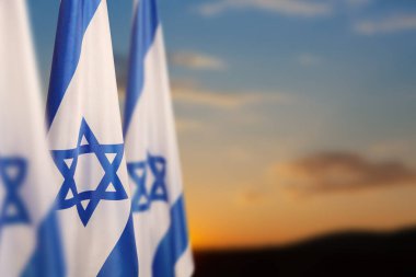 Gün batımında bulutlu arka planda David 'in bir yıldızıyla İsrail bayrakları. Ulusal devlet sembolleriyle İsrail hakkında vatansever bir kavram. Metin için yeri olan pankart.