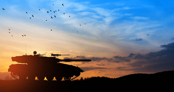 Силуэт армейского танка на фоне заката. Военная техника.