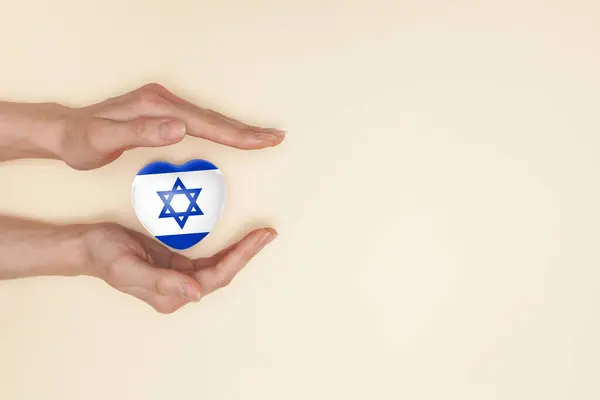 Stock image Heart with print of Israel flag in female hands. Flat lay. Copy space.