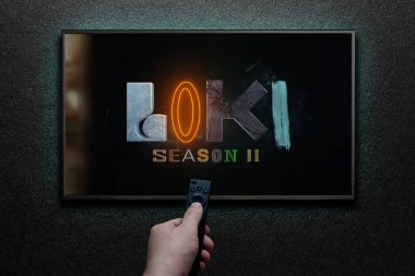 Amerikan televizyon dizisi Loki fragmanı ya da TV ekranındaki film. Adam uzaktan kumandayla televizyonu açıyor. Astana, Kazakistan - 5 Ekim 2023.