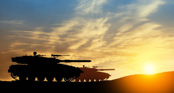 Силуэты армейских танков на фоне заката. Военная техника.
