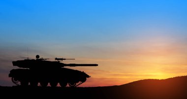Silhouette of army tank at sunset sky background. Military machinery.