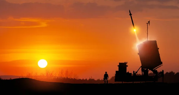 Israel\'s Iron Dome air defense missile launches. Silhouettes of soldier and Israel\'s Iron Dome air defense. The missiles are aimed at the sky at sunset. Missile defense.