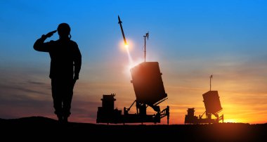 İsrail 'in Demir Kubbe hava savunma füzeleri fırlatıldı. Asker siluetleri ve İsrail 'in Demir Kubbe hava savunması. Füzeler günbatımında gökyüzüne nişan alınmıştır. Füze savunması.