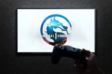 Televizyonda Mortal Kombat 1 oyunu var. Elinde av alanı var. Siyah desenli duvarda ışık var. Astana, Kazakistan - 2 Temmuz 2023.