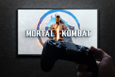 Televizyonda Mortal Kombat 1 oyunu var. Elinde av alanı var. Siyah desenli duvarda ışık var. Astana, Kazakistan - 2 Temmuz 2023.