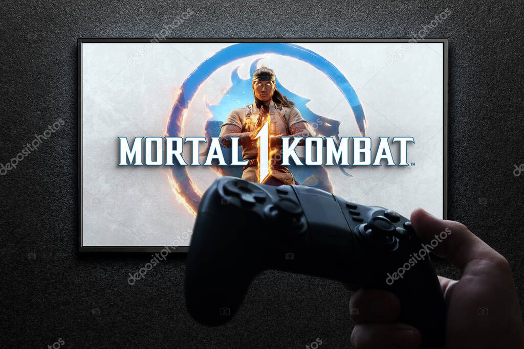 Mortal Kombat 1 game on TV screen with gamepad in hand on black textured wall with light. Astana, Kazakhstan - July 2, 2023.