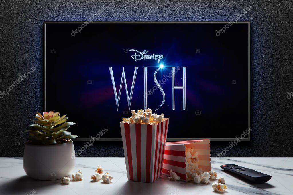Wish trailer or movie on TV screen. TV with remote control, popcorn boxes and home plant. Astana, Kazakhstan - November 15, 2023.