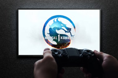 Televizyonda Mortal Kombat 1 oyunu var. Elinde av alanı var. Siyah desenli duvarda ışık var. Astana, Kazakistan - 2 Temmuz 2023.