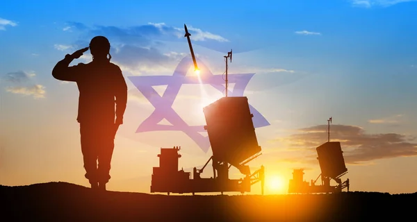 Israel's Iron Dome air defense missile launches. Silhouettes of soldier and Israel's Iron Dome air defense. The missiles are aimed at the sky at sunset with Israel flag. Missile defense.