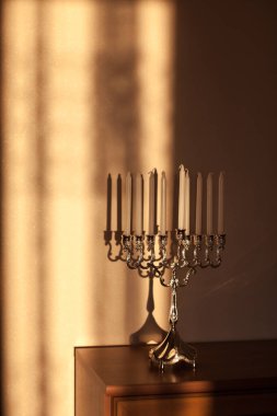 Hanuka menorası ya da gün batımında gün batımında Yahudi bayramı için gün ışığında Hanukkiah. Hanuka lambası, dokuz dallı şamdan ve duvarında gölgesi olan mumlar..