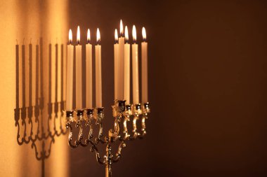 Hanuka menorası ya da gün batımında gün batımında Yahudi bayramı için Hanukkiah. Hanuka lambası, dokuz dallı şamdan. Duvarında gölgesi olan yanan mumlar..