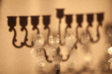 Hanuka menorasının gölgesi, ya da Hanukkiah. Yahudi bayramı Hanuka arkaplanı. Hanuka lambasının gölgesi, mumsuz dokuz dallı şamdan odak dışı. Seçici odak.