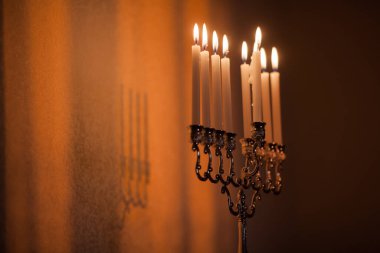 Hanuka menorası ya da gün batımında gün batımında Yahudi bayramı için Hanukkiah. Hanuka lambası, dokuz dallı şamdan. Duvarında gölgesi olan yanan mumlar..