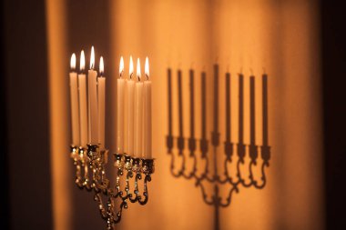 Hanuka menorası ya da gün batımında gün batımında Yahudi bayramı için Hanukkiah. Hanuka lambası, dokuz dallı şamdan. Duvarında gölgesi olan yanan mumlar..