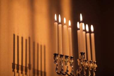Hanuka menorası ya da gün batımında gün batımında Yahudi bayramı için Hanukkiah. Hanuka lambası, dokuz dallı şamdan. Duvarında gölgesi olan yanan mumlar..