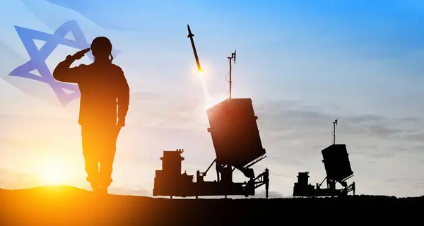 Israel\'s Iron Dome air defense missile launches. Silhouettes of soldier and Israel\'s Iron Dome air defense. The missiles are aimed at the sky at sunset with Israel flag. Missile defense.