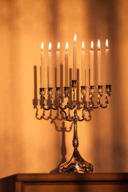 Hanuka menorası ya da gün batımında gün batımında Yahudi bayramı için gün ışığında Hanukkiah. Hanuka lambası, dokuz dallı şamdan. Duvarında gölgesi olan yanan mumlar..