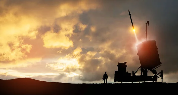 Israel's Iron Dome air defense missile launches. Silhouettes of soldier and Israel's Iron Dome air defense. The missiles are aimed at the sky at sunset. Missile defense.