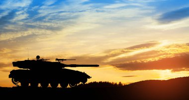 Silhouette of army tank at sunset sky background. Military machinery.