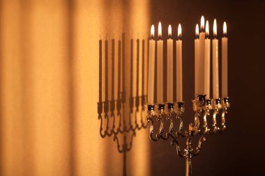 Hanuka menorası ya da gün batımında gün batımında Yahudi bayramı için Hanukkiah. Hanuka lambası, dokuz dallı şamdan. Duvarında gölgesi olan yanan mumlar..