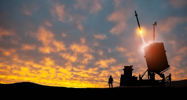 Israel\'s Iron Dome air defense missile launches. Silhouettes of soldier and Israel\'s Iron Dome air defense. The missiles are aimed at the sky at sunset. Missile defense.