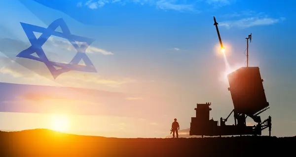 Israel\'s Iron Dome air defense missile launches. Silhouettes of soldier and Israel\'s Iron Dome air defense. The missiles are aimed at the sky at sunset with Israel flag. Missile defense.