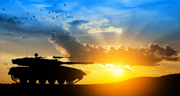 Силуэт армейского танка на фоне заката. Военная техника.
