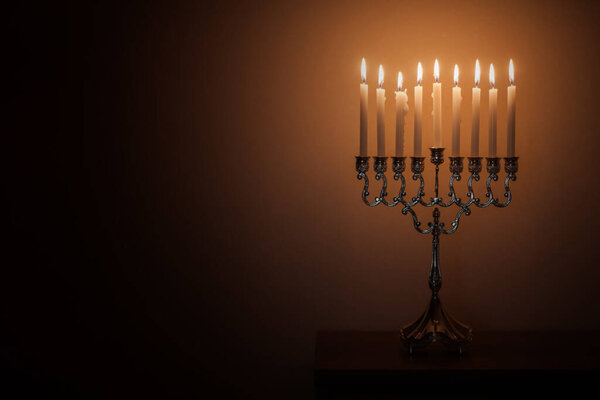 Hanukkah menorah, or hanukkiah in the light of the sun at sunset for Jewish holiday Hanukkah. Hanukkah lamp, nine-branched candelabrum with burning candles.