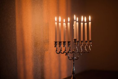Hanuka menorası ya da gün batımında gün batımında Yahudi bayramı için Hanukkiah. Hanuka lambası, dokuz dallı şamdan. Duvarında gölgesi olan yanan mumlar..