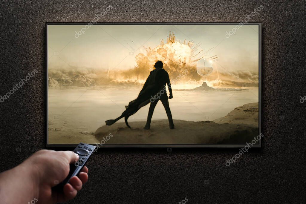 TV screen playing Dune Part Two trailer or movie. Man turns on TV with remote control. Astana, Kazakhstan - May 15, 2023.