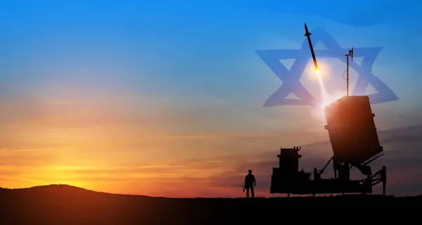 Israels Iron Dome air defense missile launches. Silhouettes of soldier and Israels Iron Dome air defense. The missiles are aimed at the sky at sunset with Israel flag. Missile defense.