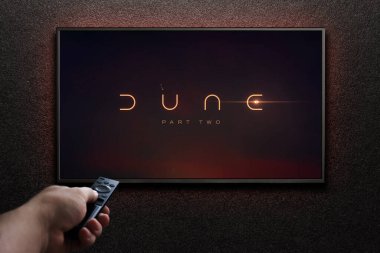 TV ekranında Dune Part Two fragmanı ya da film oynanıyor. Adam uzaktan kumandayla televizyonu açıyor. Astana, Kazakistan - 15 Mayıs 2023.