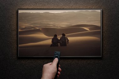 TV ekranında Dune Part Two fragmanı ya da film oynanıyor. Adam uzaktan kumandayla televizyonu açıyor. Astana, Kazakistan - 15 Mayıs 2023.